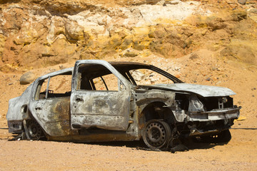 Crashed car wreck in desert landscape.