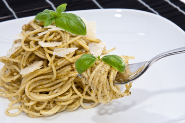 Heap of spaghetti with fresh pesto on dark background