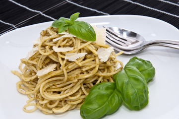 Heap of spaghetti with fresh pesto on dark background