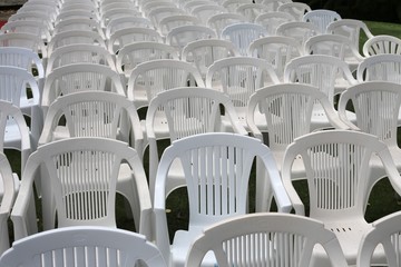 Empty white plastic chairs at outdoor venue