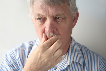 senior man strokes his mustache