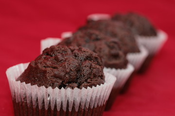 Four chocolate muffins in row over the red background