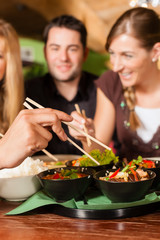 Young people eating in Thai restaurant