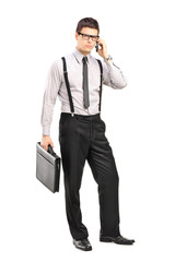 Stylish young man holding a breifcase and  talking on a mobile p