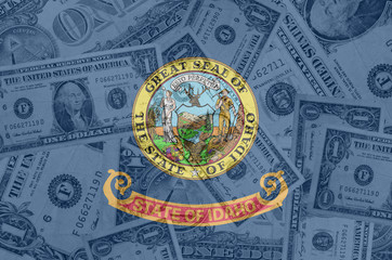 US state of idaho flag with transparent dollar banknotes in back