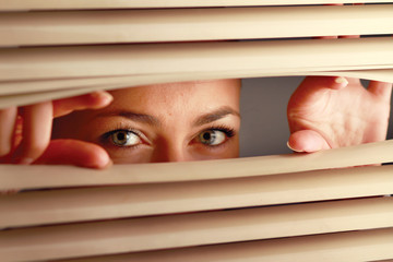 Portrait of a woman looking through out the blinds