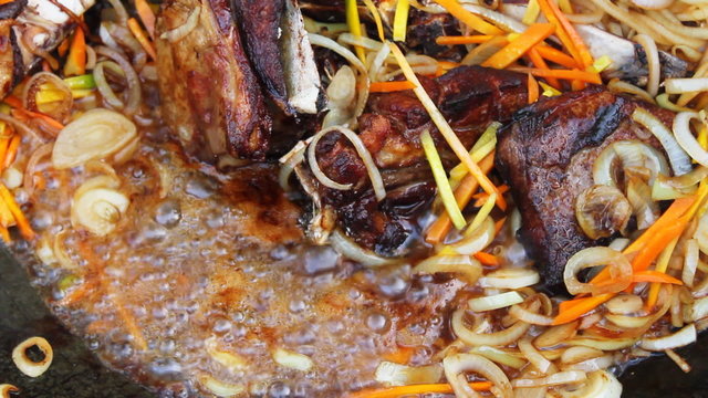 Adding carrots to kettle with cooking meat, closeup,