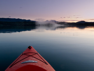 Paddling in a kayak through calm sunset waters