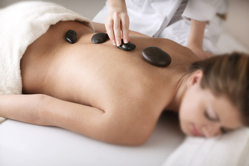 Young woman enjoying a back massage with hot stone in a spa