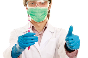 A male dentist with a toothbrush and showing ok