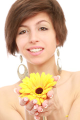 A smiling woman is holding a yellow gerbera
