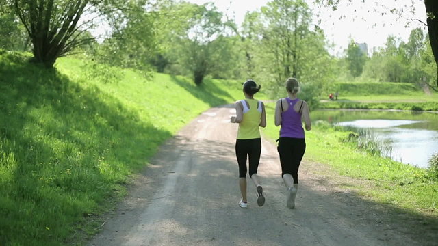Two young girls jogging in the park, slow motion