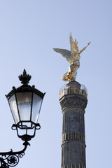 Fototapeta na wymiar Back view in vertical composition of The Golden Angel on top of the Victory Column reflects the sunlight; it is a monument located in Berlin, in center of the 