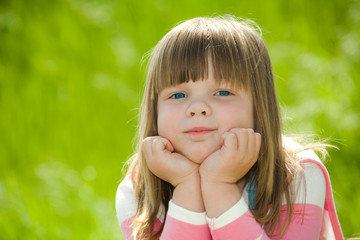 little girl wearing pink blouse on green summer grass