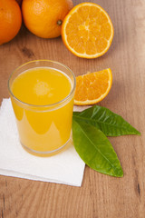 vaso con zumo de naranja, naranjas y hojas verdes