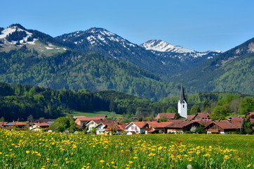 Dorf in frühlingshafter Alpenlandschaft