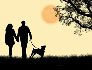 Silhouette of a couple walking their dog on sunset