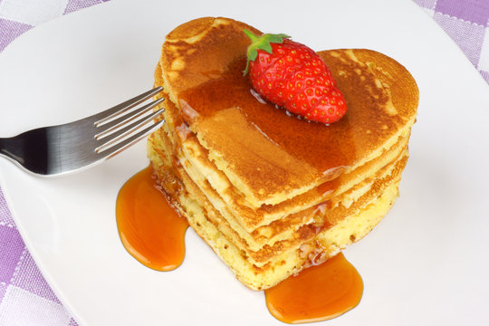 Heart-shaped pancakes with syrup and strawberry