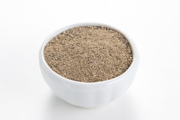 Black pepper ground (Piper nigrum) in a white bowl on white back