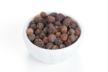 Black pepper (Piper nigrum) in a white bowl on white background.