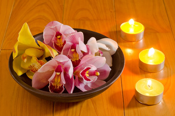 Obraz na płótnie Canvas Cymbidium kwiaty i świece herbaty na talerzu
