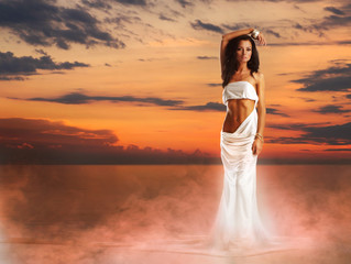 A beautiful young woman posing in a long white dress