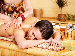 Fototapeta na wymiar White woman getting massage in bamboo spa.