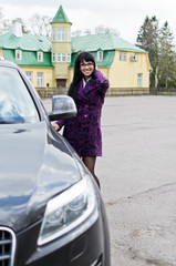 Pretty woman in a coat sits in an expensive car