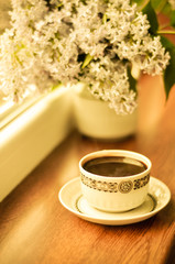 Ceramic cup with coffee and bouquet of lilac