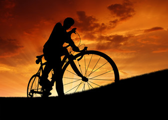 silhouette of the cyclist on road bike at sunset