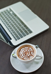 Laptop with coffee cup on wood table