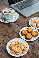 Laptop with coffee cup and snack on wood table