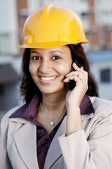 Happy female construction engineer talking on cellphone