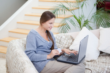 Women sitting on a sofa while using a laptop