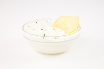 Bowl of dip with herbs with a chip dipped in it