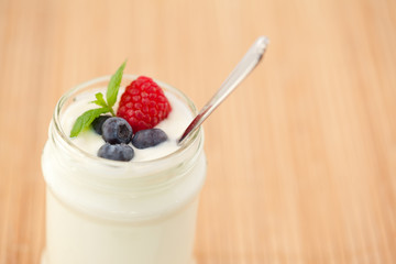 Close up of a pot yogurt with leaves red berries