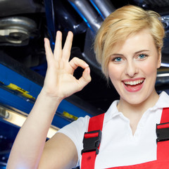 Happy apprentice is proud and shows ok in a garage