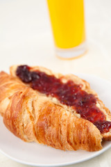 Glass of orange juice behind a croissant