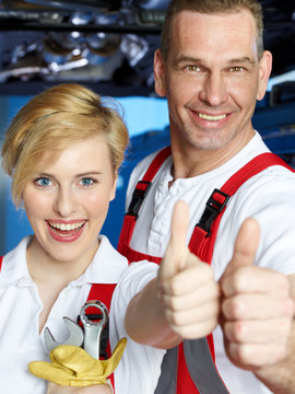 Master mechanic and female apprentice show thumbs up