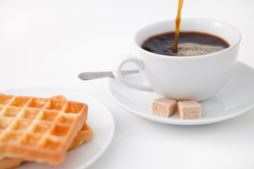 Waffles sugar and a cup of coffee on white plate