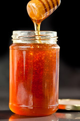 Honey sticky trickle dropping in a jar