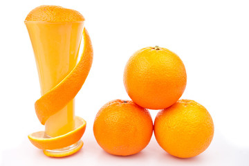 Orange peel wrapped around a glass near a pile of oranges