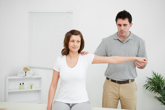 Serious practitioner extending the arm of a patient