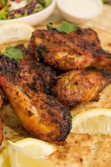 Tandoori Chicken Legs on a Naan Bread. Salad and dips.