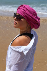 Young pretty woman at the beach with pink kerchief on her head