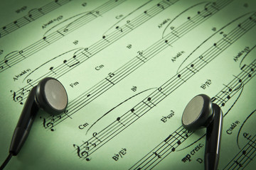 An ear phone on the top of a music sheet