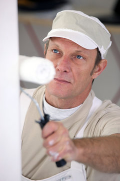 closeup picture of mature painter holding roller