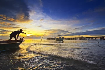 Zelfklevend Fotobehang throwing fishing net during sunset © noomhh