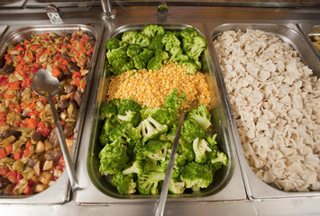 Hot trays with cooked food close-up in dining room