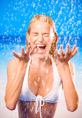 Young woman at rain or summer shower on beach
